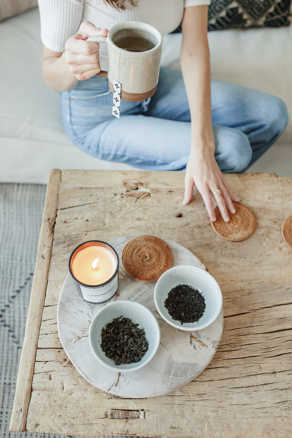 Handwoven Tenganan Coasters made from natural Ata reed placed on rustic wooden table with tea and candle.