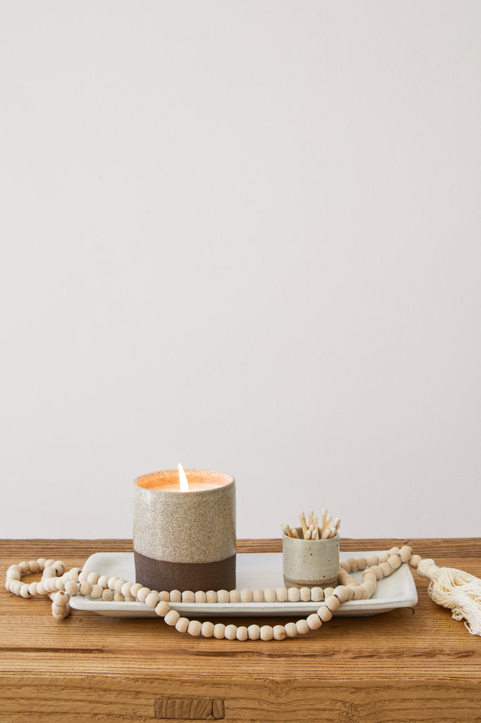 Styled view of Hanselmann Hand Thrown Ceramic Tray with Uzumati Candle, Match Striker, and Bali Beads on a vintage console with a white background. - Saffron and Poe