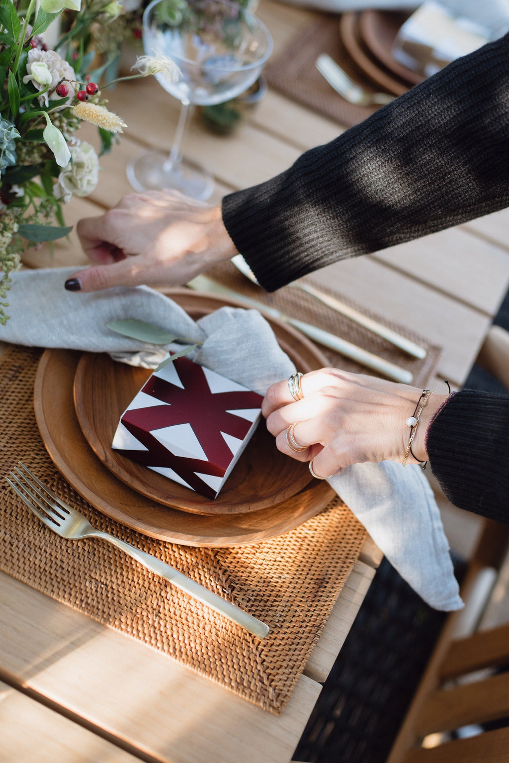 Hand-carved teak plate on wooden table with napkin and decorative box, styled for elegant dining setting