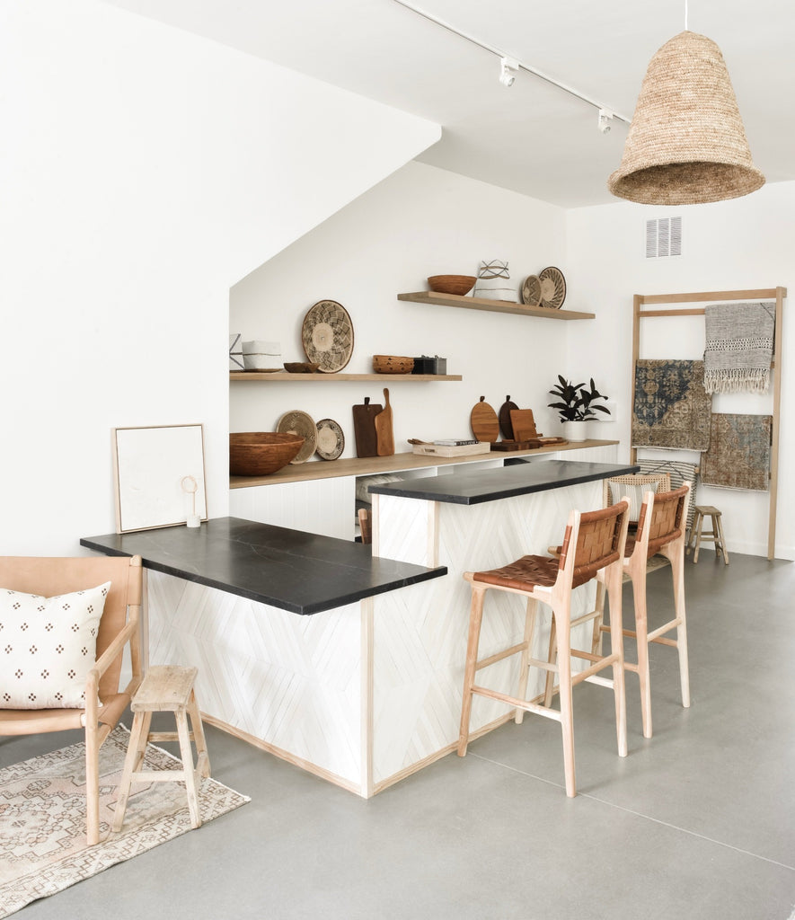 Two of our Woven Leather Strap Bar Stools in Saddle and carved from teak styled in kitchen at countertop. Handcrafted in Bali. - Saffron and Poe