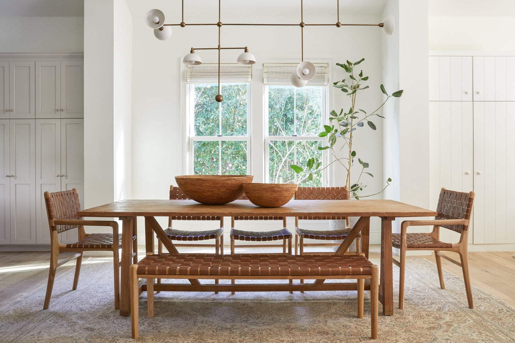 Woven Tenganan basket used as centerpiece on wooden dining table with woven chairs and bench in bright room