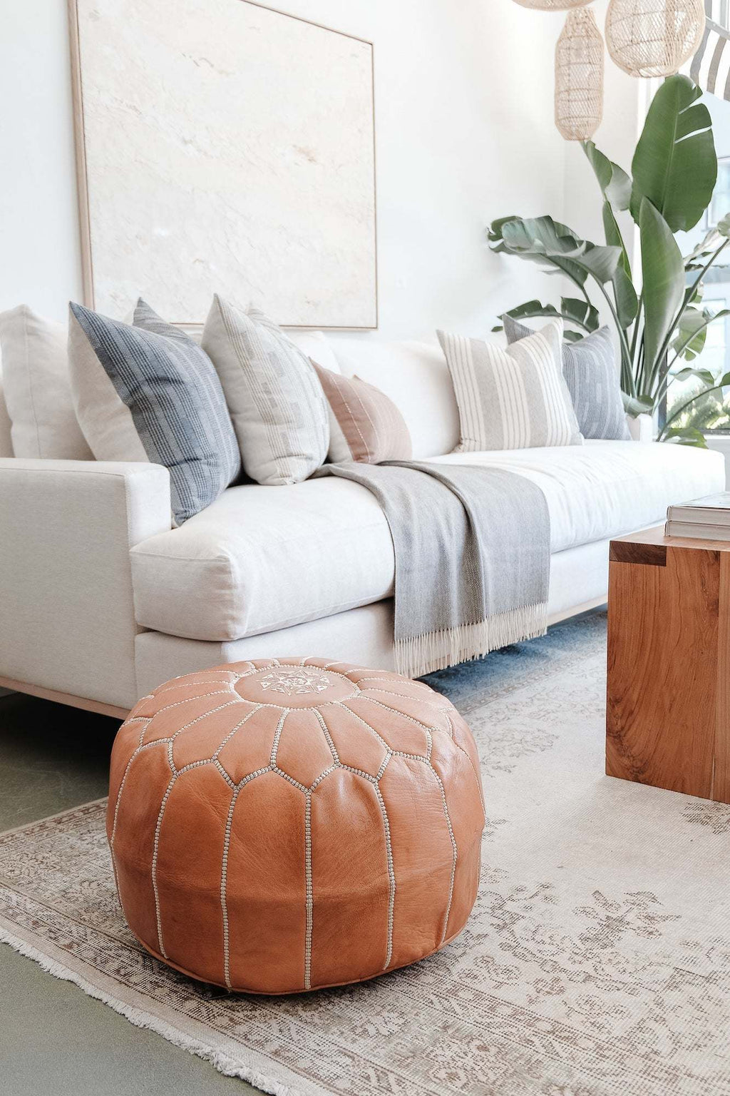 Embroidered Moroccan leather pouf in a modern living room with white sofa and decorative pillows