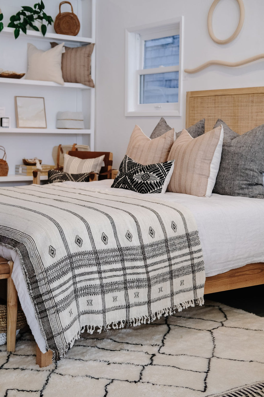 Handwoven Bhujodi Blanket with black pastoral motifs on a bed in a cozy modern bedroom
