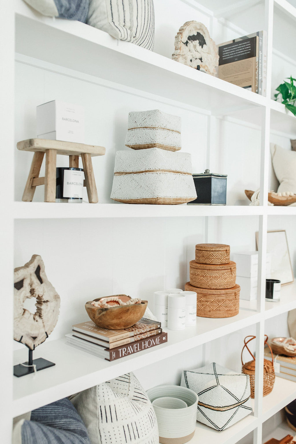 White shelves with decorative travel-inspired home decor and the book Travel Home displayed