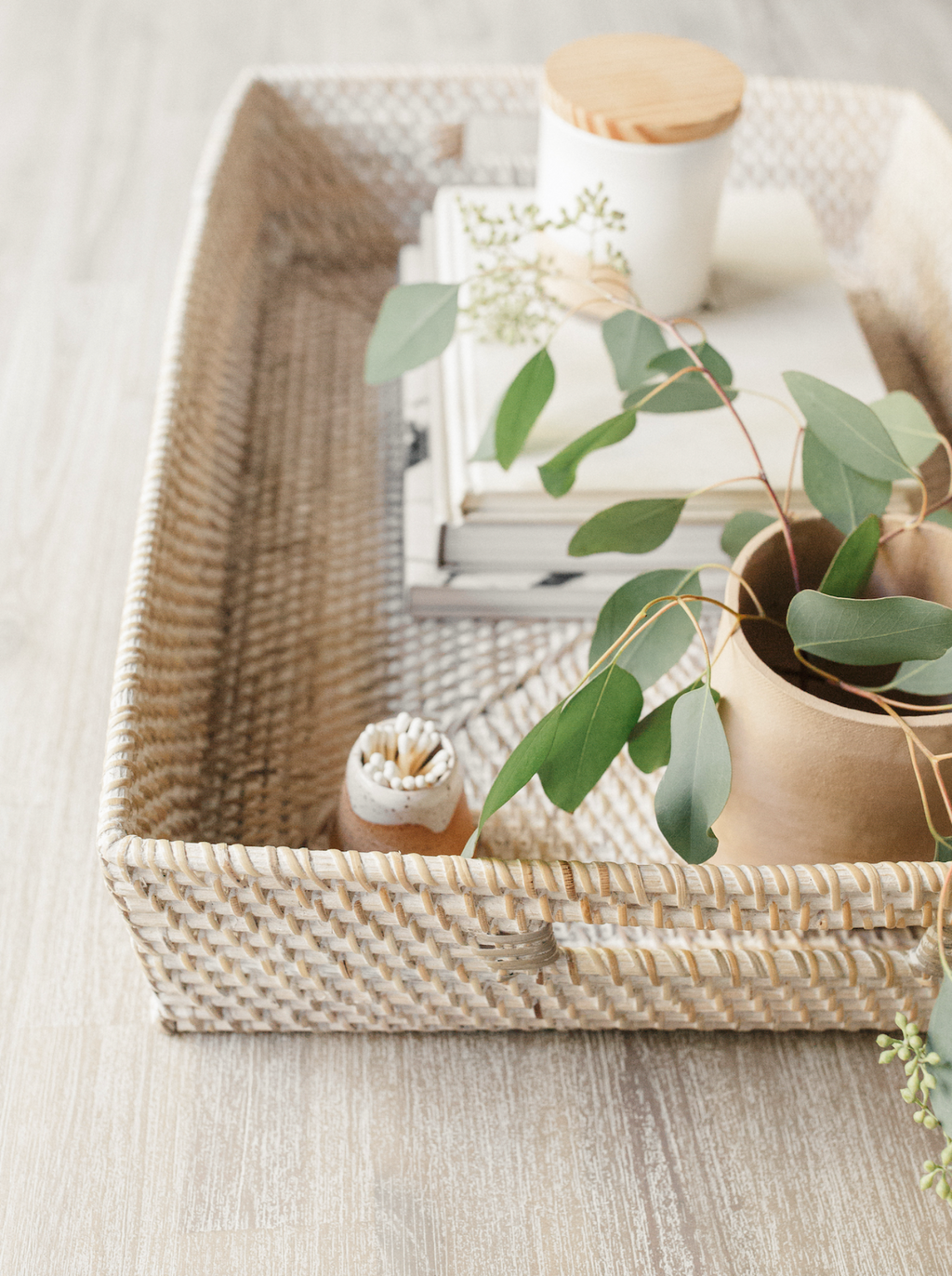 Whitewashed handwoven Lombok basket tray with decor and greenery on light wood surface