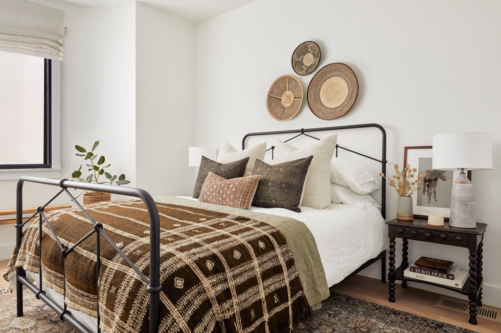 Ilala palm wall baskets with traditional patterns displayed above a bed in a cozy bedroom setting
