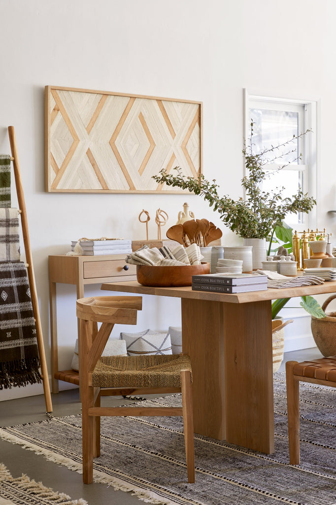 Styled side view of our Rattan Curved Back Dining Chair next to our Oak Dining Table with our Moroccan Flat Weave Kilim Rug, Oak Console Table and Aleksandra Zee Art Work. - Saffron and Poe