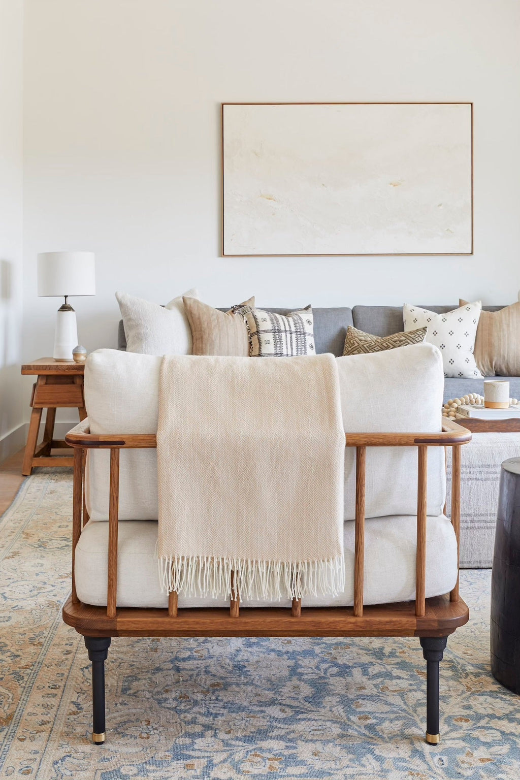 Beige baby alpaca throw blanket with fringe draped over modern wooden chair in stylish living room