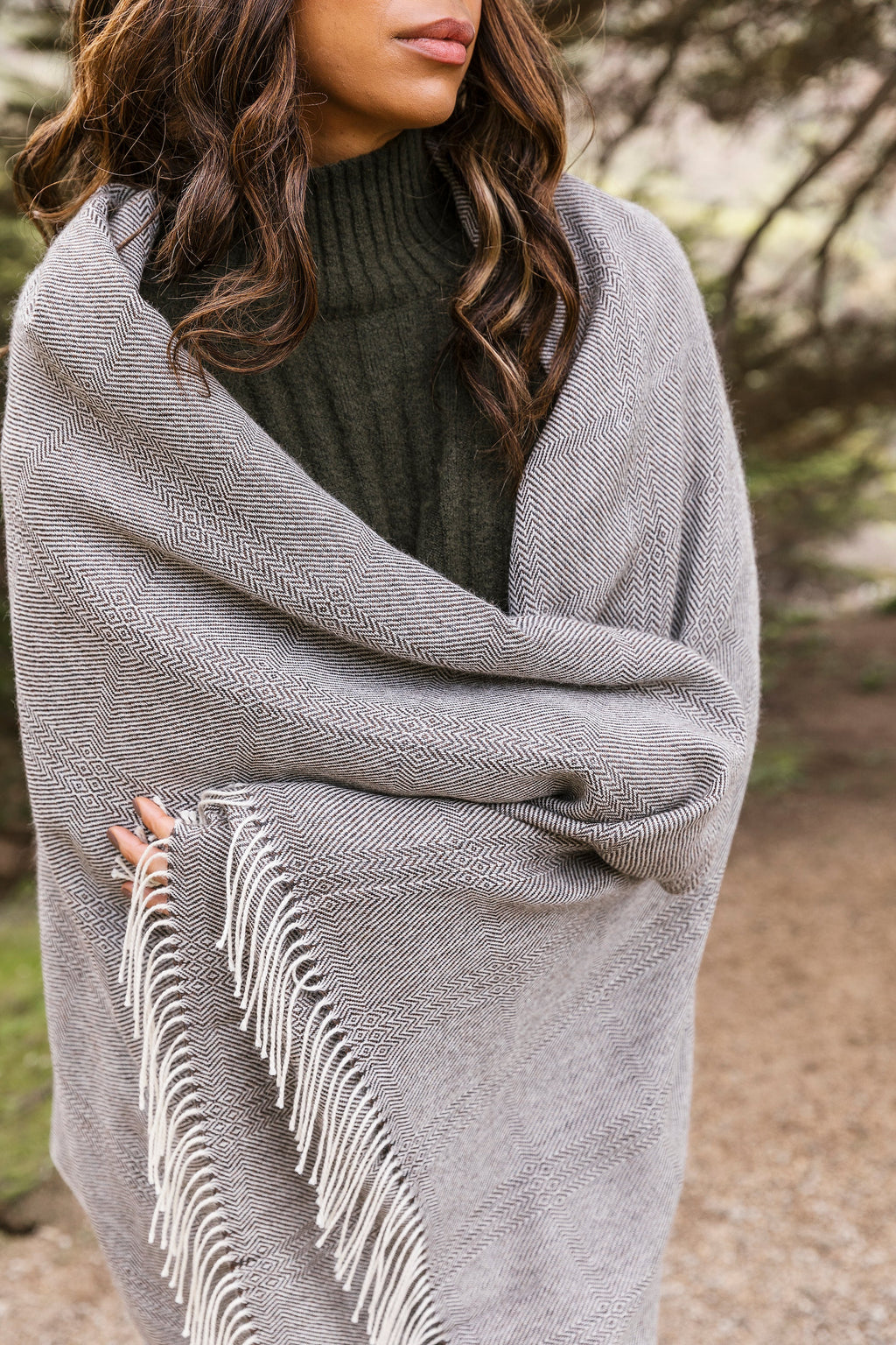 Charcoal brown baby alpaca throw blanket with fringe worn as shawl outdoors