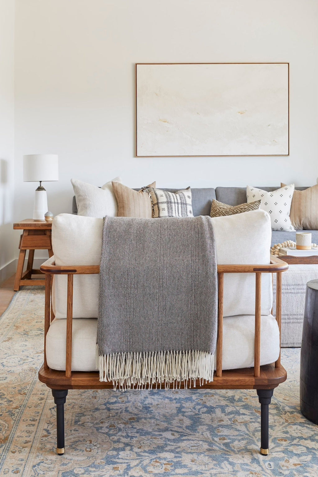 Charcoal brown baby alpaca throw with fringe draped over modern wooden sofa in cozy living room