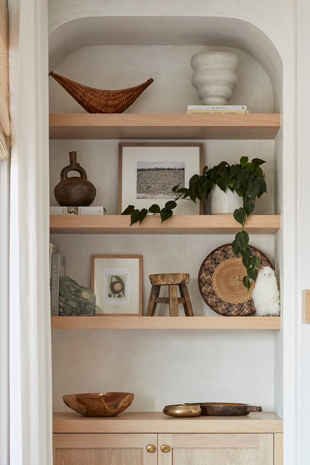 Neutral-toned shelving with natural decor, plants, and a white Alpaquita stuffed animal