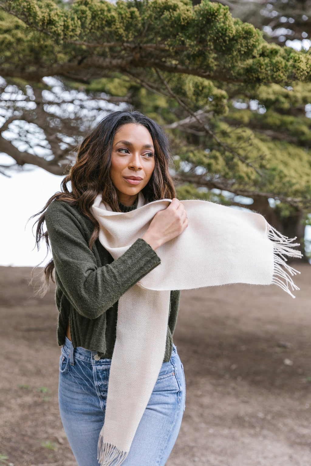 Woman outdoors wearing a beige baby alpaca scarf with fringe on each end