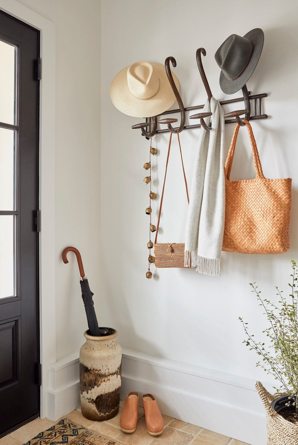 Gray baby alpaca scarf hanging on wall hook in stylish entryway with hats and woven bag