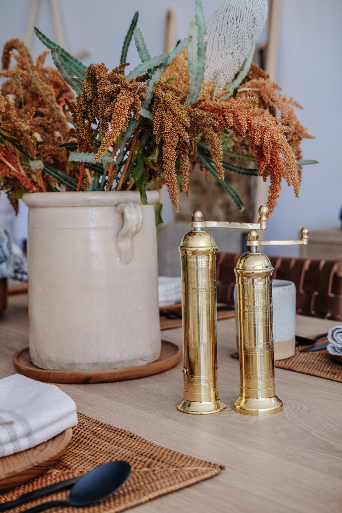 Styled Brass Grinders on an Oak Dining Table next to an Italian Confit Pot and Tenganan placemats. - Saffron and Poe