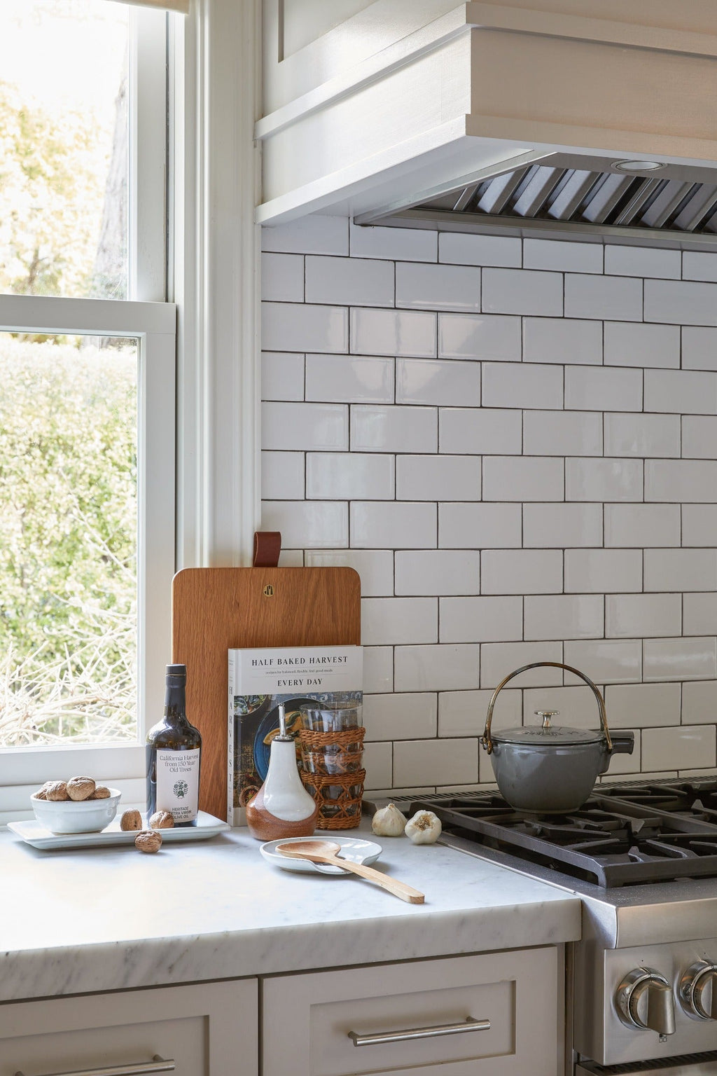 Uzumati Ceramic Olive Oil Bottle on kitchen countertop with white subway tile backsplash and cooking utensils