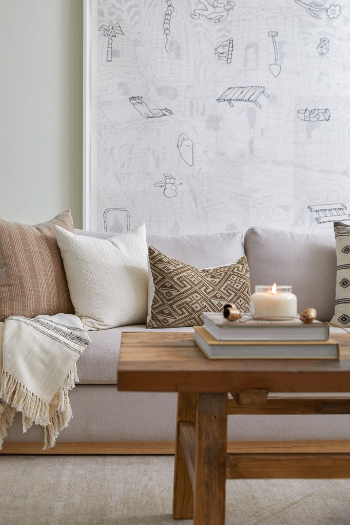 Handwoven Colombian Grey Stripe Throw styled on a sofa with Beige Embroidered Pillow, Antique Miao Lumbar Pillow, and Ivory Embroidered Pillow . - Saffron + Poe