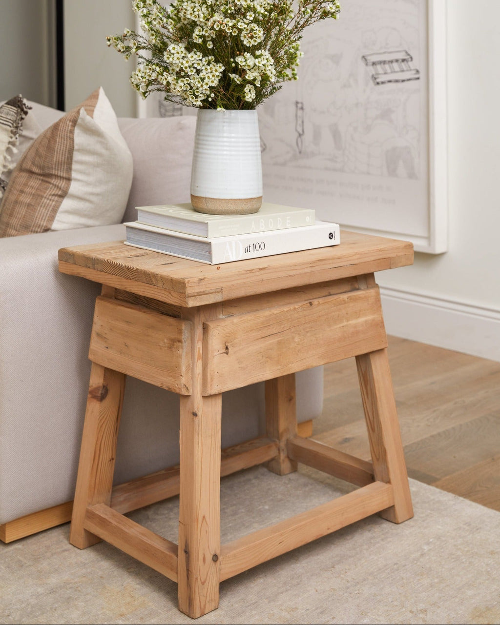 Vintage end table made of reclaimed cedar wood with a rustic, antique Chinese design, styled with a vase of flowers and books in a modern living room.