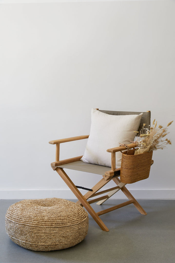 Styled view of Taupe Canvas Director's Chair with Natural Woven Pouf, Director's Pillow, and Tenganan Side Basket against white background on concrete flooring. - Saffron and Poe