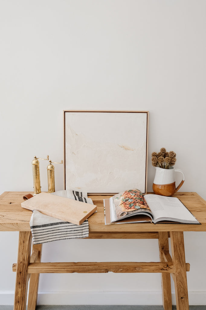 Styled Studio Inko's Bird's Eye Maple Cutting and Serving Board with a linen hand towel and brass grinders against a white wall. - Saffron and Poe