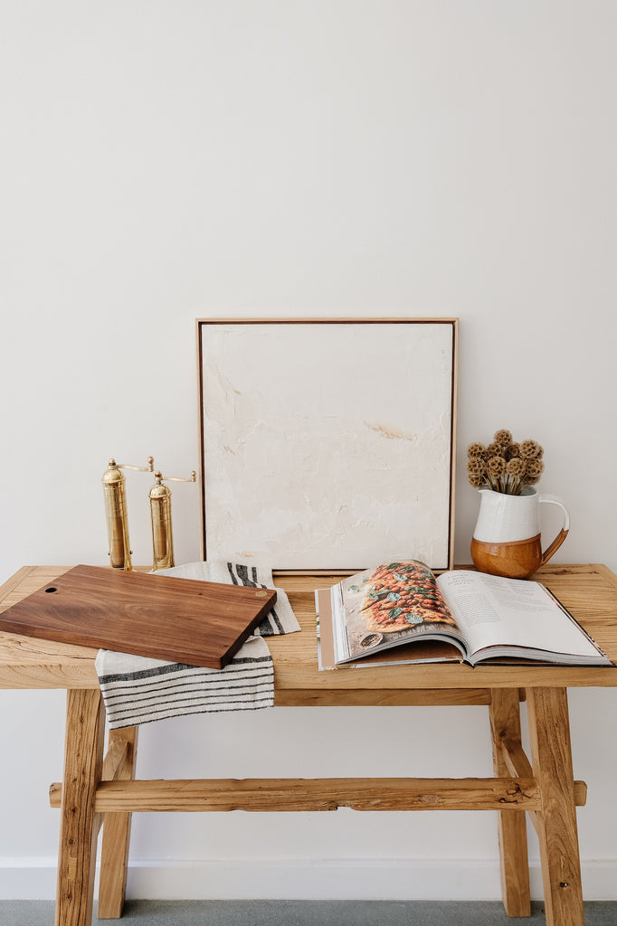 Styled Studio Inko Walnut Cutting and Serving Board with a linen hand towel and brass grinders against a white wall. - Saffron and Poe