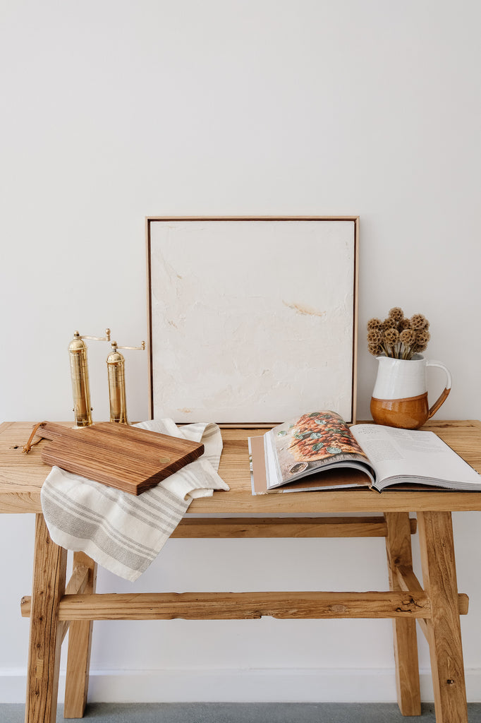 Styled Studio Inko Zebrawood Cutting and Serving Board with linen hand towel and brass grinders against a white wall. - Saffron and Poe