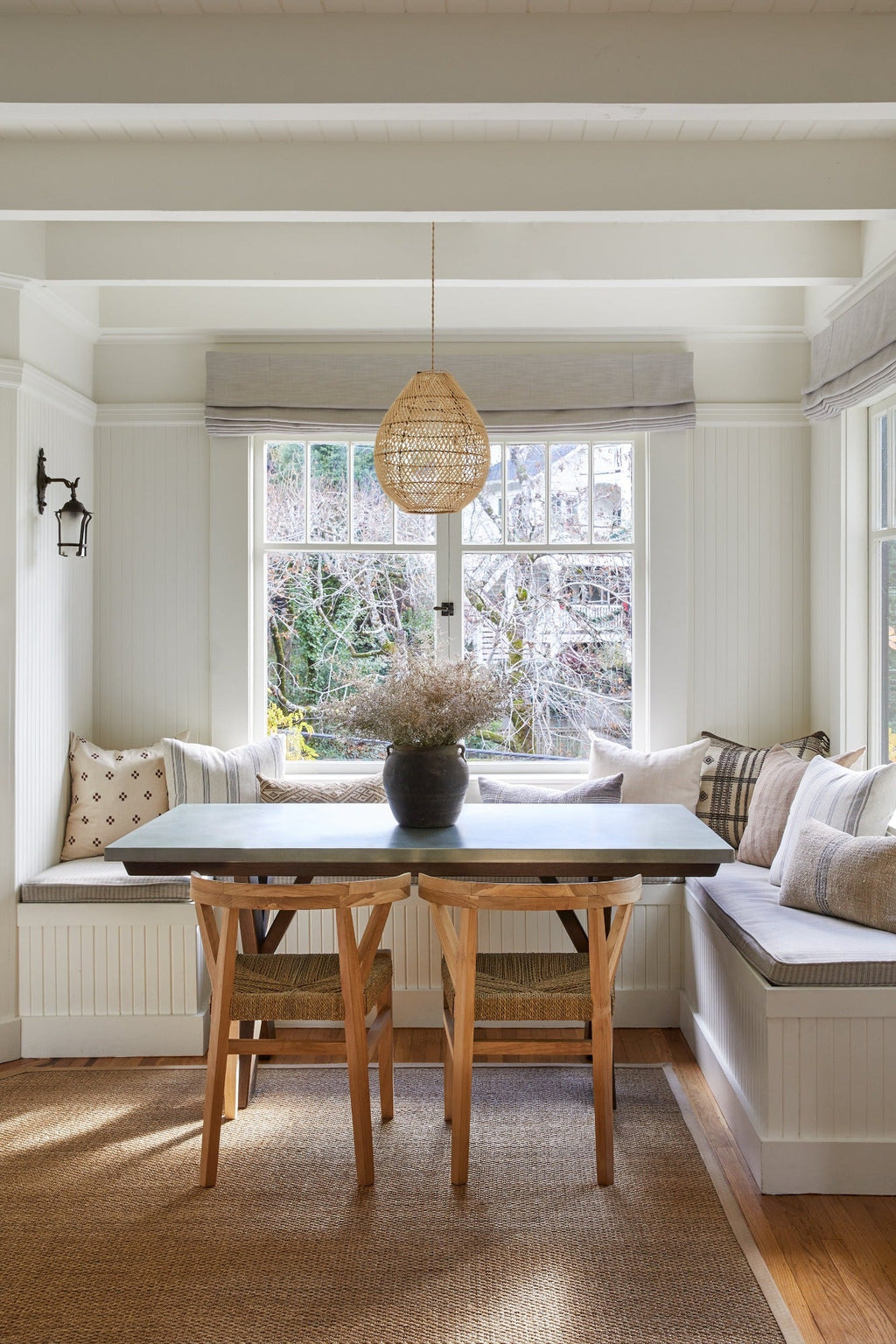 Teardrop Basket Pendant woven rattan light fixture hanging above dining table in cozy, bright nook with wooden chairs and cushioned bench seating