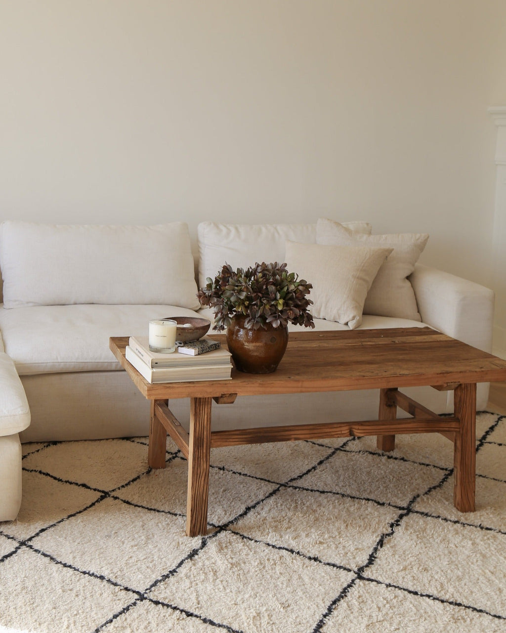 Vintage wood coffee table made of reclaimed elmwood in a living room with white sofa and patterned rug