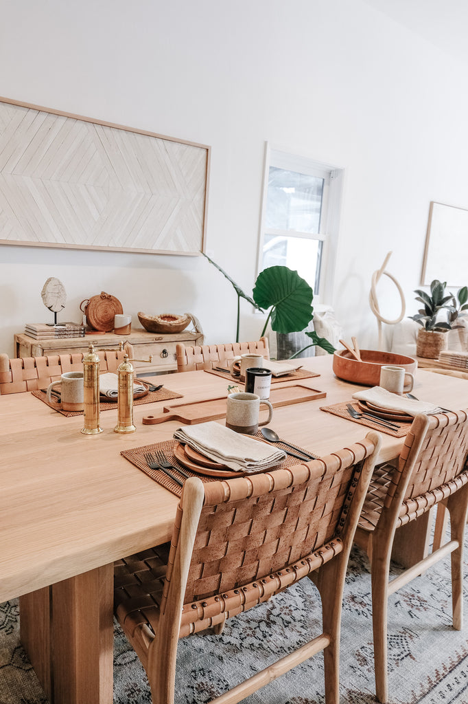 Close up view of Woven Tenganan Placemat on an Organic Edge Oak Dining Table with Woven Leather Strap Dining Chairs - Beige. - Saffron and Poe