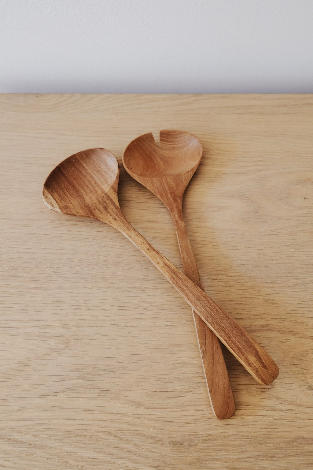 Hand-carved teak salad servers on wooden surface