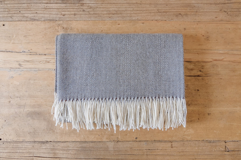 Front view of Grey Baby Alpaca Throw on an oak table. - Saffron and Poe