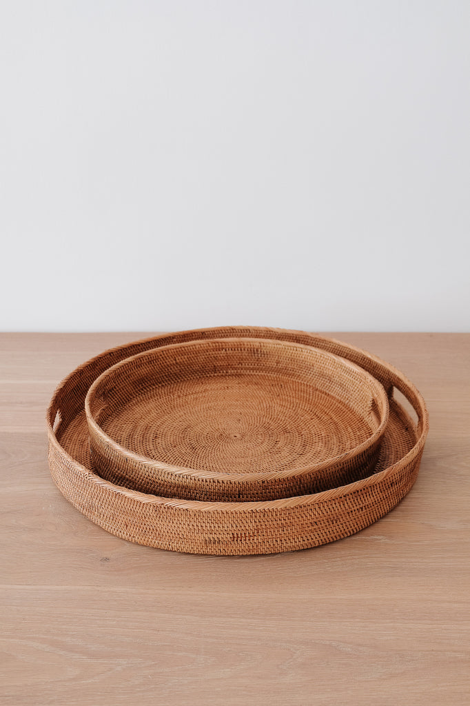 Slightly angled front view of Round Tenganan Basket Trays on a white oak table against a white wall. - Saffron and Poe
