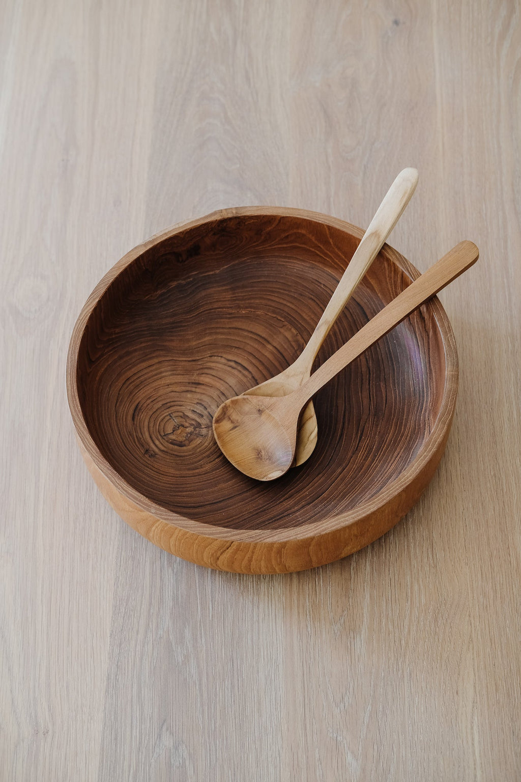 Hand-carved teak salad bowl with wooden salad utensils showcasing natural wood grain and swirls