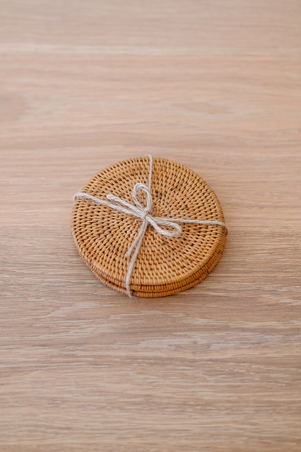 Set of four handwoven Tenganan Coasters made from natural Ata reed, tied with string on a wooden surface