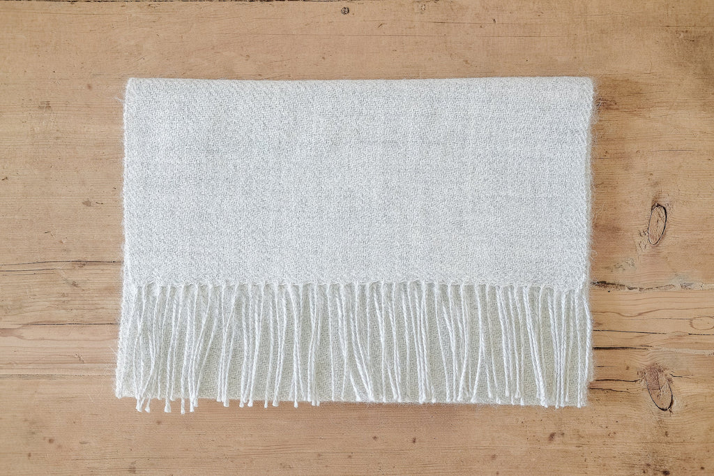 Gray baby alpaca scarf with long twisted fringe on wooden surface