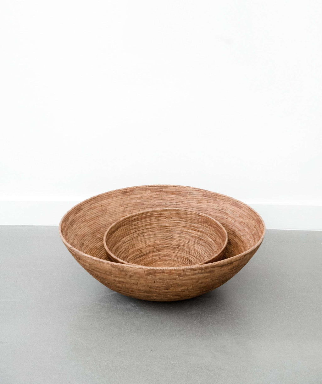 Woven Tenganan basket made from natural Ata reed with intricate weaving and warm golden hue placed on a gray surface