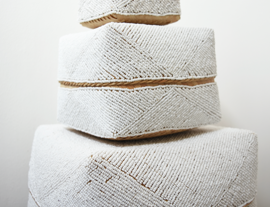 Stack of hand-beaded Bali baskets in solid white with geometric patterns on woven bamboo