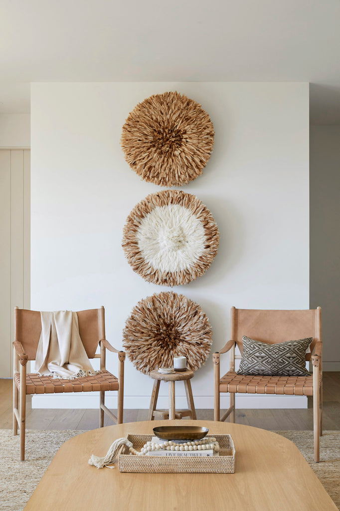 Styled Leather Strap Safari Lounge in a neutral living room with wall baskets, an Alpaca Throw Blanket, an Antique Miao Lumbar Pillow, a Lombok Tray, and Bali Beads. - Saffron and Poe