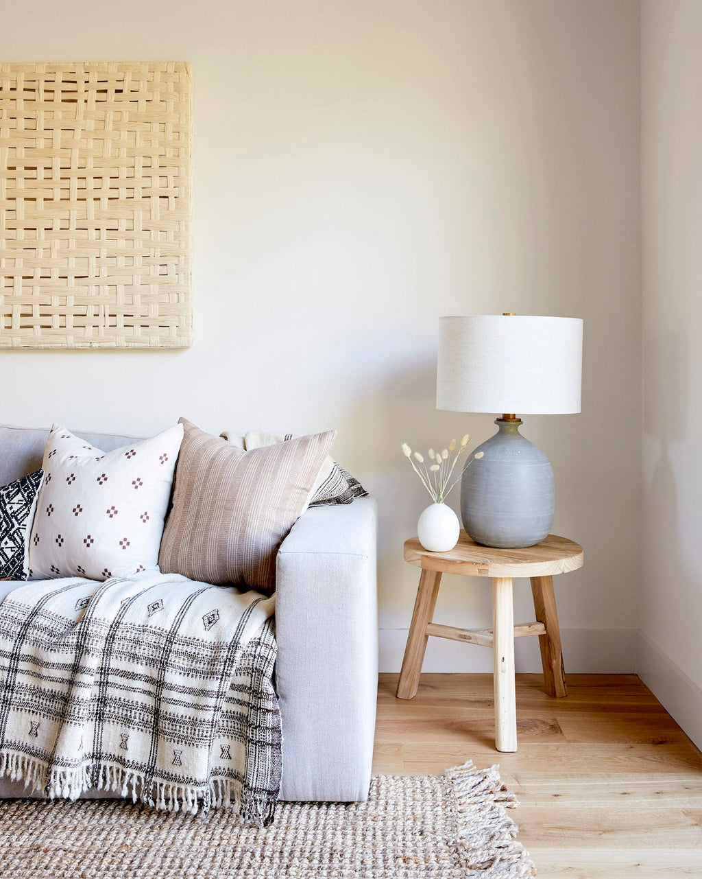 Vintage round side table made of reclaimed elmwood with lamp and decorative vase beside sofa in cozy living room